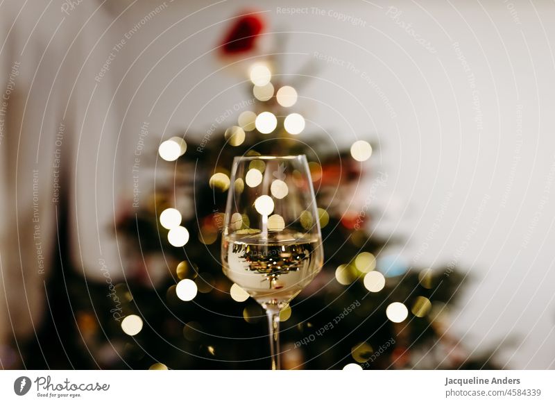 Wine glass with wine in front of a Christmas tree with bokeh Vine Fairy lights Adorned reflection Christmas & Advent Illuminate Christmas decoration