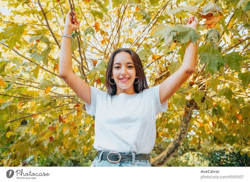 African arab young girl between green leaves smiling. Pointing Copy space for text and adds. Trendy clothes, Jeans and white tshirt modern styling. Social networks