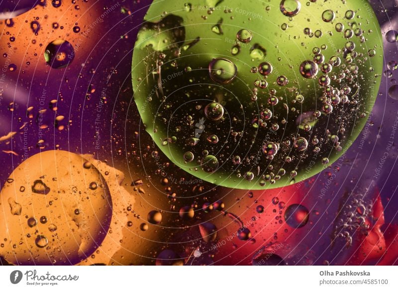 Unusual colorful background with oil drop circles and air bubbles that reflect yellow, orange, purple, green and red colors. Color spots intentionally unfocused. Cosmic space and galaxy made of oil.