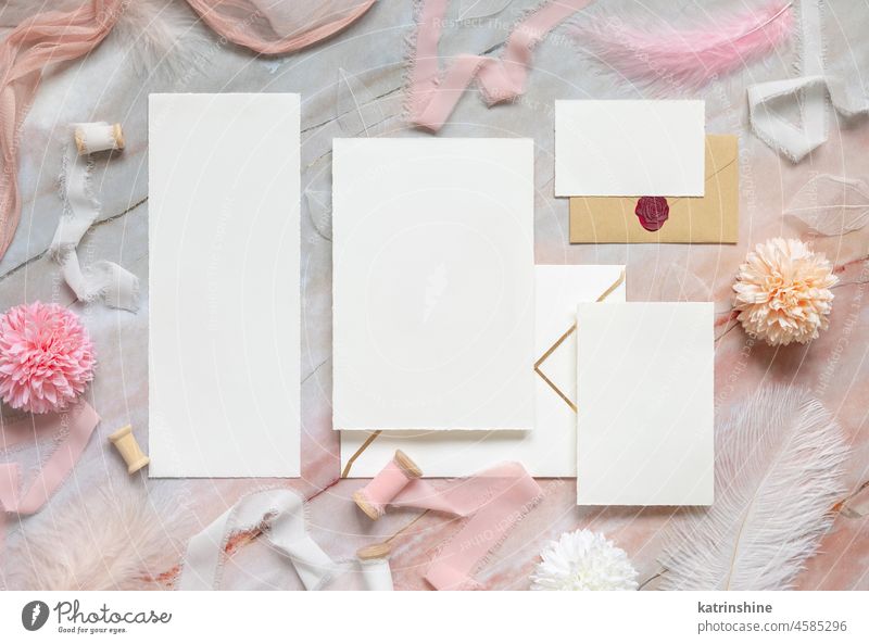 Wedding cards and envelopes between pastel flowers, silk ribbons and feathers on marble WEDDING mockup Flowers pink top view girlish suite set valentine white