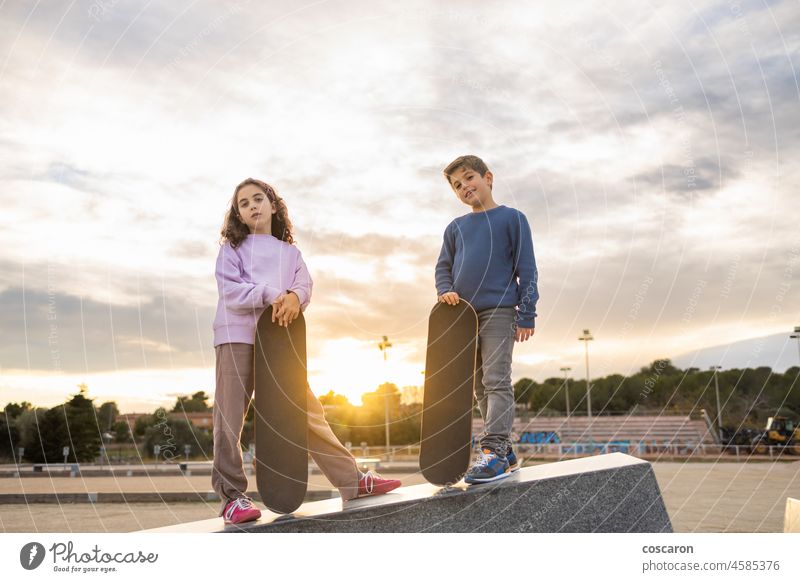 Two kids with a skate board at sunset action active activity boy child children couple face female friends friendship fun girl happy leisure lifestyle outdoor