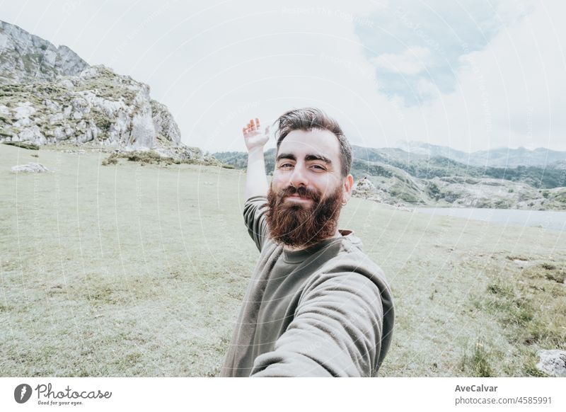 Bearded man taking selfie on the mountain during hiking in mountains. Traveler bearded man using mobile phone application. Travel and lifestyle horizontal