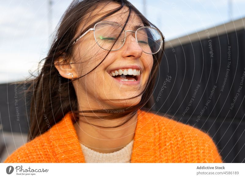 Young cheerful female in eyeglasses relaxing with closed eyes woman dreamy wind wavy hair positive casual content cardigan calm happy comfort enjoy knitted