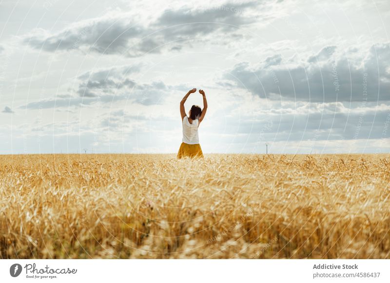 Anonymous woman standing in wheat field nature countryside summer rural skirt natural plantation female brunette calm sky cloudy peaceful meadow lady short hair