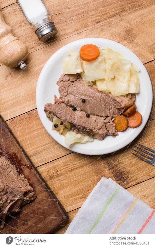 Delicious sliced corned beef with cabbage and pieces of carrot meat serve wooden table plate appetizing tasty meal vegetable delicious dish garnish food gourmet