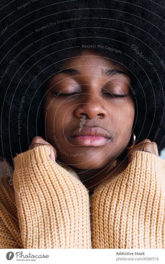 Black woman with her hands resting on her face with eyes closed portrait afro appearance funny female black african american curly hair young home positive