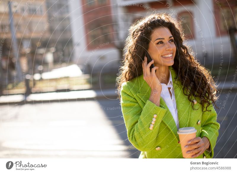 Young woman using smartphone on the street and holding takeaway coffee beautiful people beautiful woman casual cellphone cheerful city city life city street
