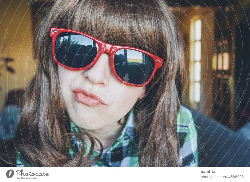 Funny portrait of a young woman wearing red sunglasses fun funny face nerd nerdy weird close headshot close up plaid freak home dreamy possitive expression