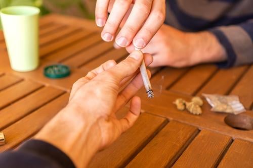 Unrecognized person passing a marijuana joint to his friend during a party. cannabis weed share together meet cigarette partner group outdoor celebration 420