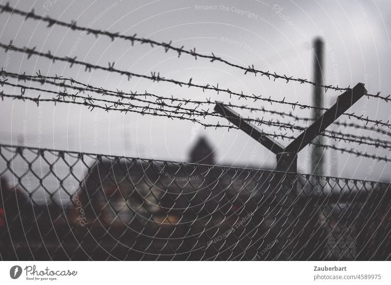Barbed wire and fence in front of warehouse building Fence Border Storage Building somber Threat Dismissive antagonistic Barrier Barbed wire fence Captured