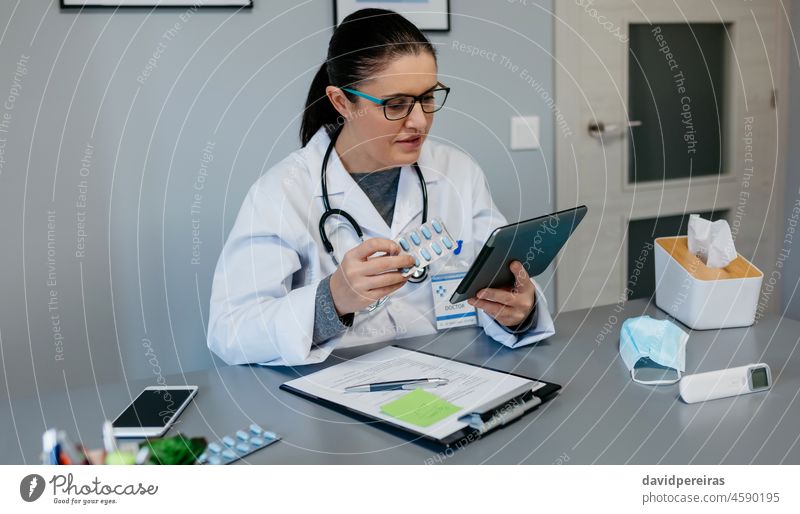 Female doctor reading drug leaflet on tablet female pills treatment learning medicament looking for information online telemedicine omicron delta med tech