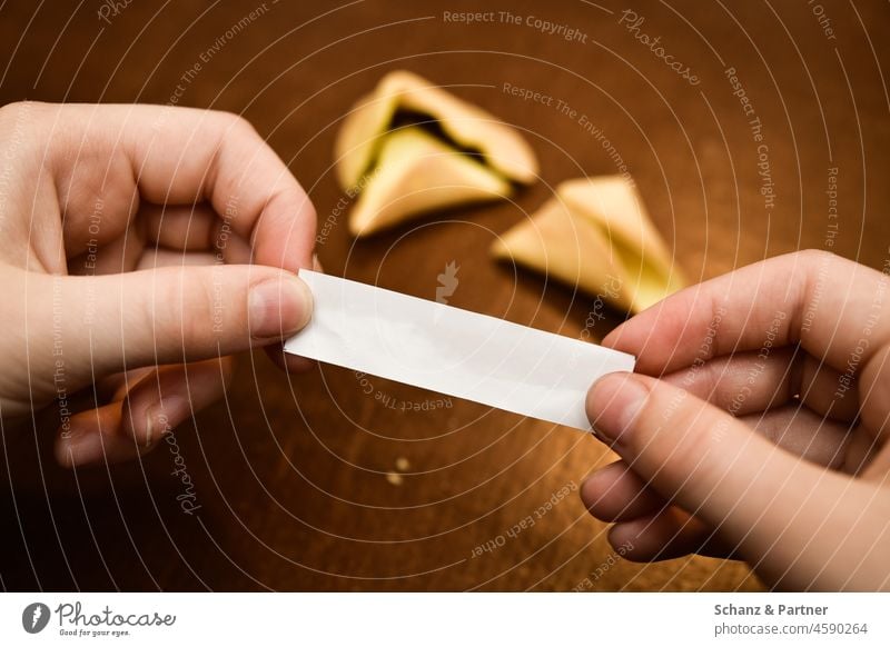 Hands hold note from fortune cookie Happy Fate Asian Fortune cookie Fingers hands Piece of paper saying Wisdom