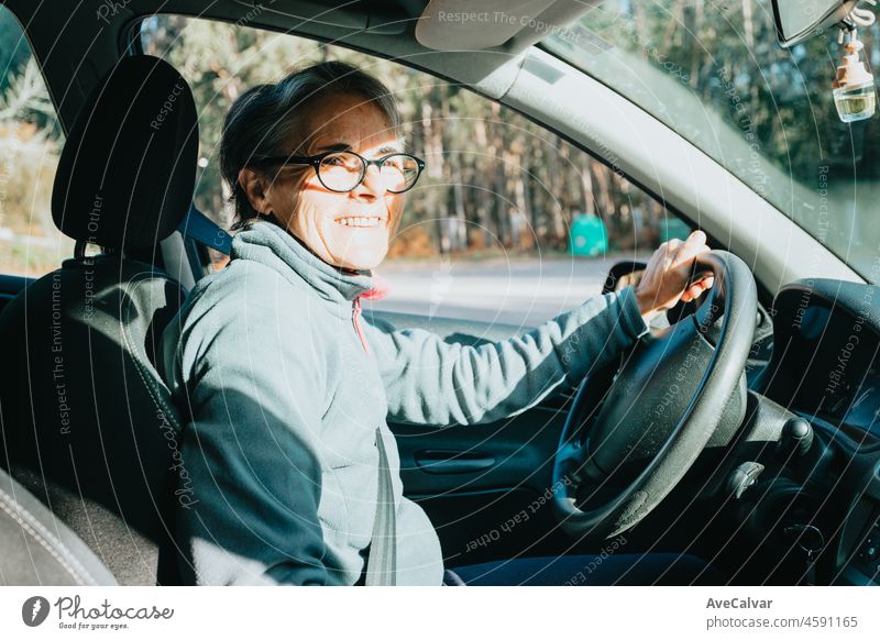 Portrait of a happy smiling senior woman learning to drive a car. Safety drive. Learning new hobby, habit and skill for this new year. Elderly person approving the driving license.