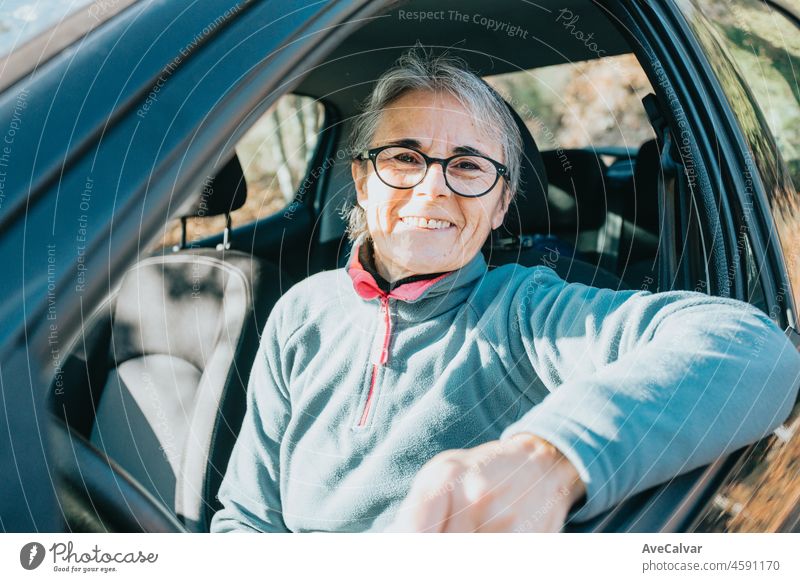 Portrait of a happy smiling senior woman learning to drive a car. Safety drive. Learning new hobby, habit and skill for this new year. Elderly person approving the driving license.