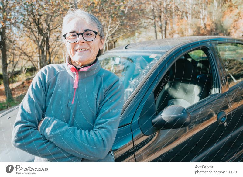 Portrait of a happy smiling senior woman outside car learning to drive a car. Safety drive. Learning new hobby, habit and skill for this new year. Elderly person approving the driving license.