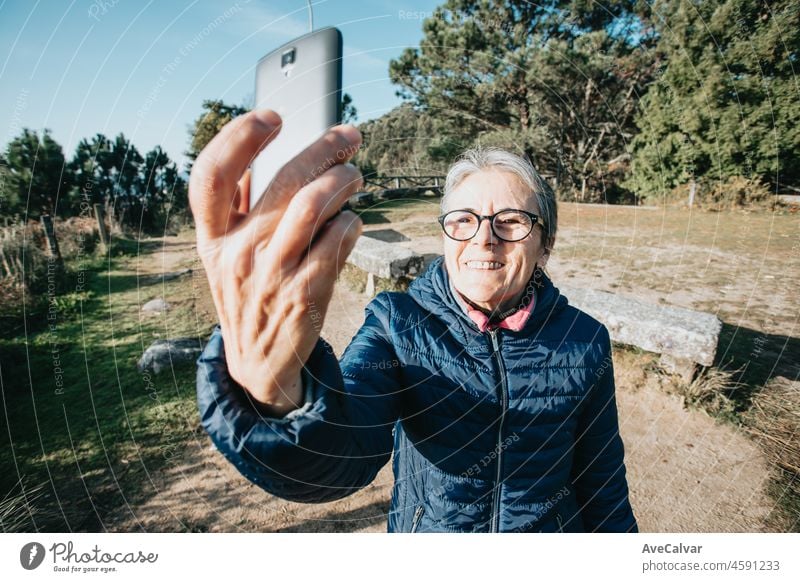 A senior old woman taking a selfie during exercise. Starts new habits for the new year. Trekking and healthy life style.Pensioner woman sport. Aging, people, active lifestyle and health concept