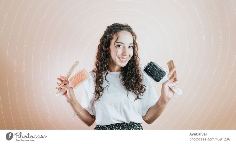 Close-up portrait young african woman nice-looking wavy-haired girl holding in hand wooden comb isolated on color pastel background. Copy space, hair concept beauty. Advertising
