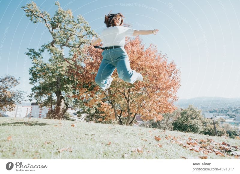 Outdoor portrait of a teenage caucasian curvy red head girl jumping on the park with freedom. Happiness, rejoices and joyful freedom people concept person