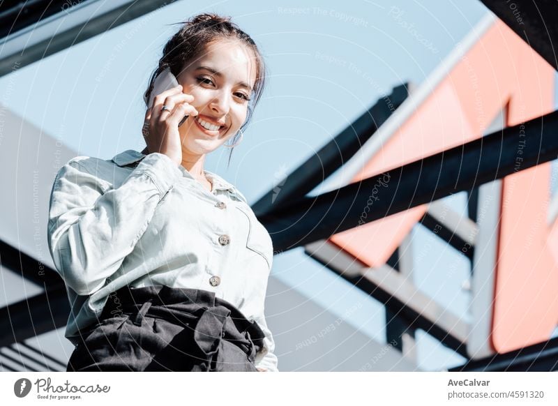 Young african arab business professional making a phone call outside office building during a sunny day.Dressed in stylish suit standing outdoors financial office,young woman lawyer copy space
