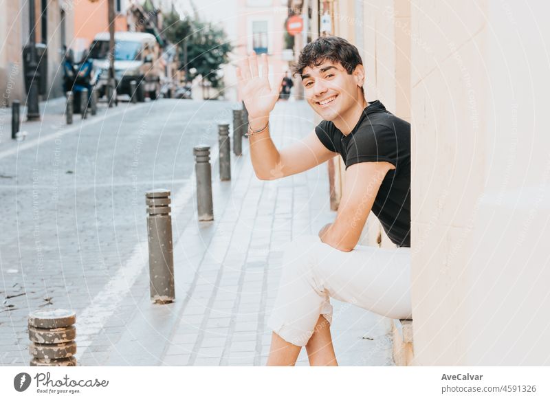 Cheerful man greeting at camera outdoors with copy space. City of madrid. Happy life style concept. Happy with new habits looking at camera happiness bonding