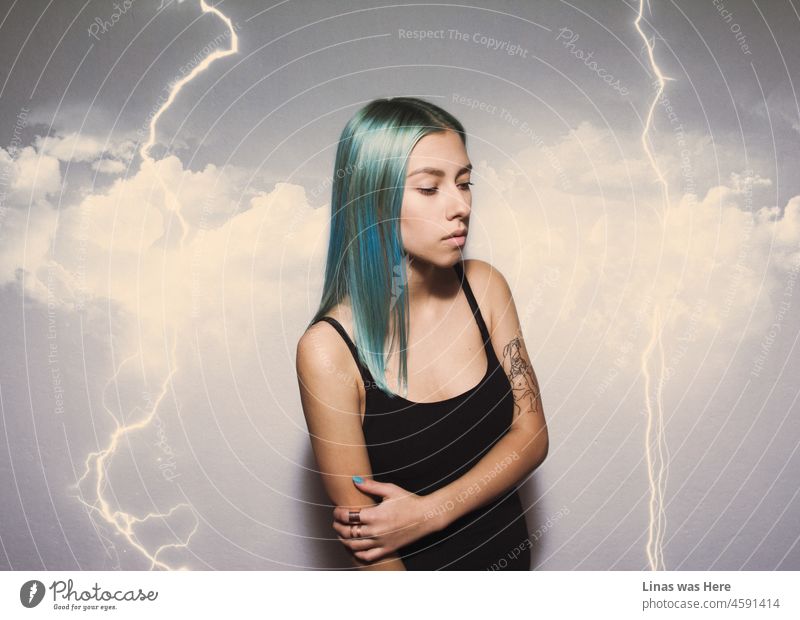 A wild electric storm is happening while a beautiful inked girl with blue hair is in the middle of it. Looking all gorgeous and stuff. Inked girl with a black blouse. Clouds can’t hide her beauty.