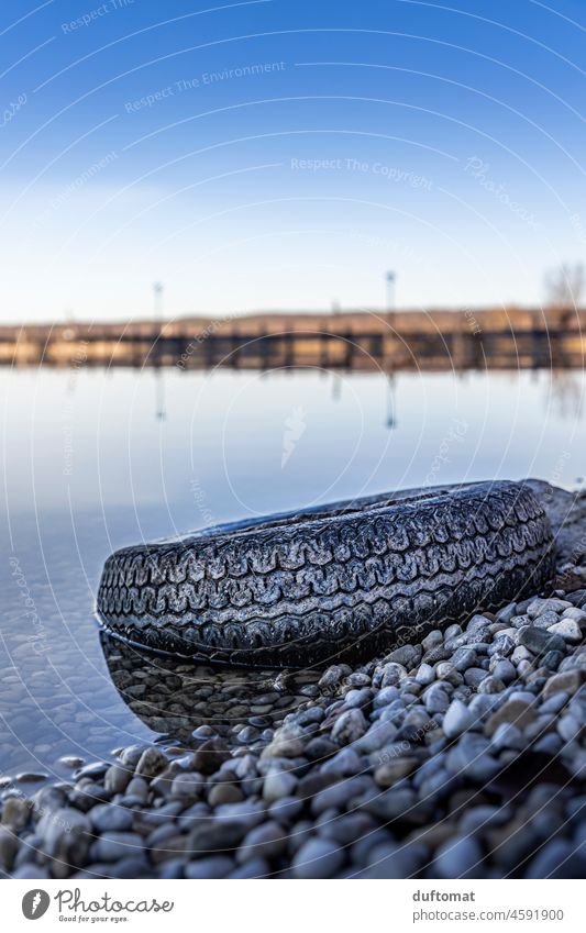 Discarded car tire lies in the water at the lake Trash Waste management forbidden Lake Nature nature conservation Refuse disposal Throw away Water