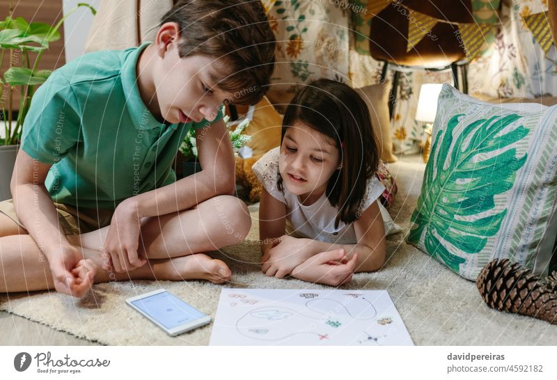 Brothers playing treasure hunting game in a diy tent at home home vacation brothers children camp fun at home map mobile compass staycation family boy girl