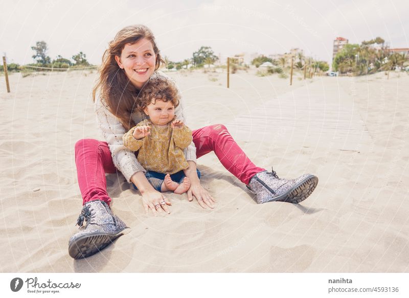 Young mom playing with her baby in the sand family motherhood vacation happiness happy playful fun funny childhood parenthood parenting casual candid life