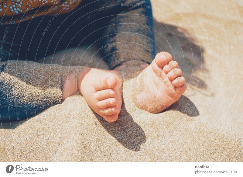 Close up of legs and feet of a baby sitting over the sun foot beach sand healthy sunny vacation holidays care skin pale white caucasian play playing fun funny