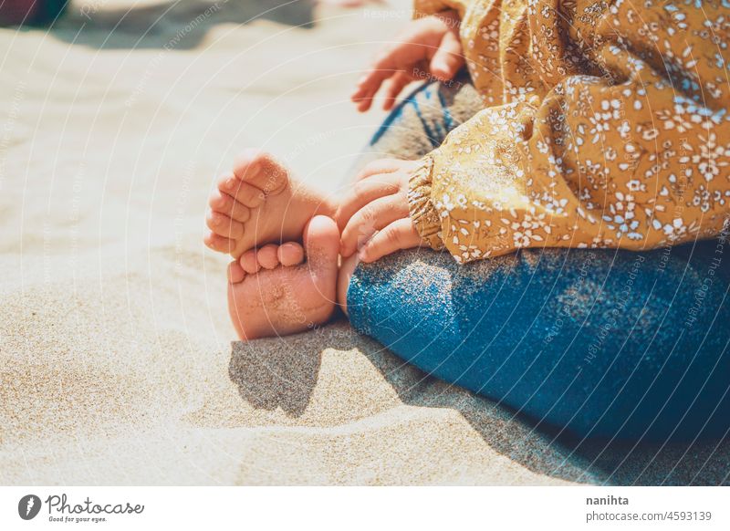 Close up of legs and feet of a baby sitting over the sun foot beach sand healthy sunny vacation holidays care skin pale white caucasian play playing fun funny