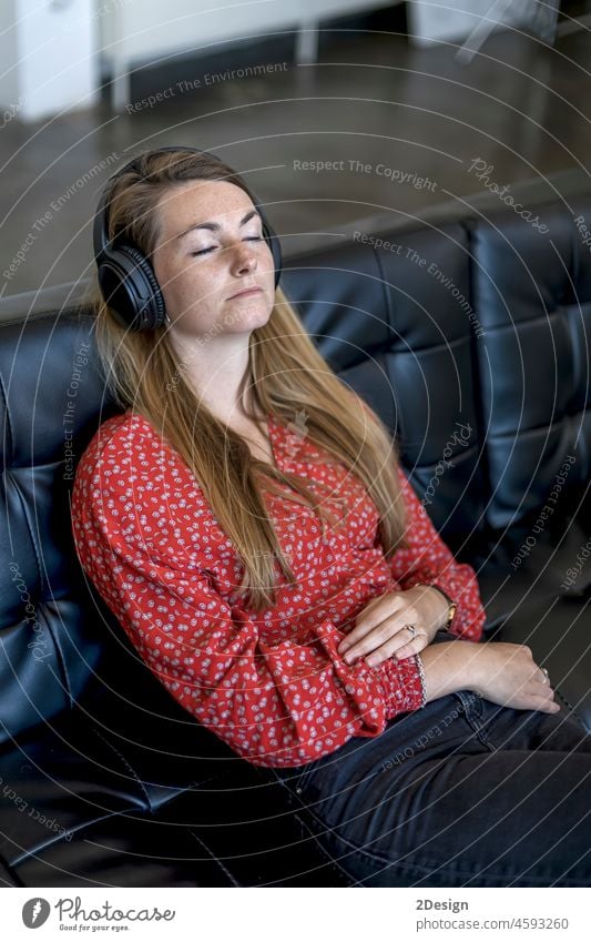 Woman at home sitting on couch wearing headphones woman sofa earphones listening music relaxation lifestyle indoor living room copy space comfortable house