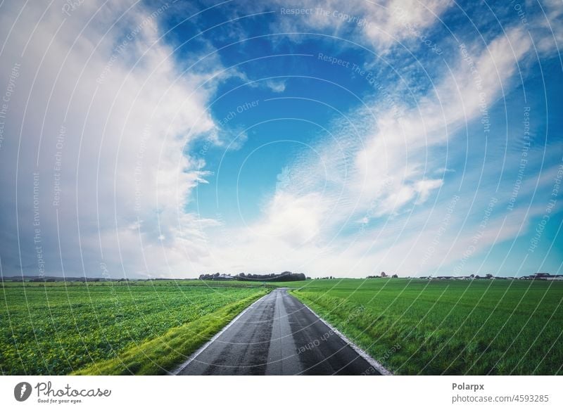 Asphalt road going through a rural landscape color automobile race cloudy speedway scenic spring background freedom plain countryside trip scenery view moving