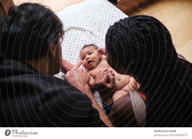 Black mother putting diapers on baby with ethnic father family change care love parenthood mom bonding caress innocent babyhood together motherhood black