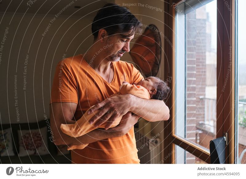 Caring ethnic father holding little baby infant caress cute bonding love tender man newborn dad bear child together childhood innocent at home hispanic stand
