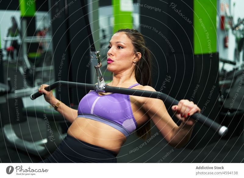 Hispanic sportswoman doing exercise on pull down machine shoulder workout gym fit training intense focus female ethnic hispanic motivation strength sporty