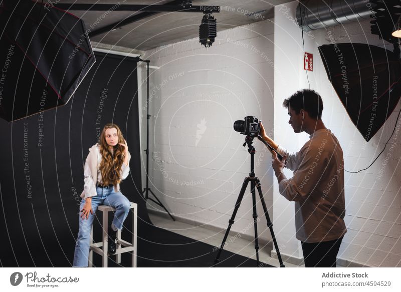 Male taking photo of female sitting on chair in professional studio woman photo camera photographer take photo equipment trendy model octabox photography
