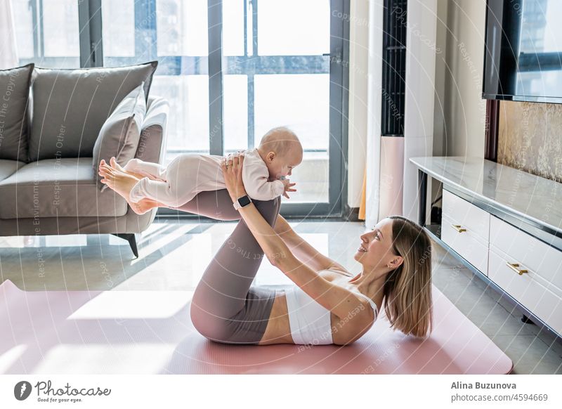 Young mother in sport clothing exercising at home with baby. Online training during coronavirus covid-19 quarantine. Stay fit and safe during pandemic lockdown. Sport, fitness, healthy concept