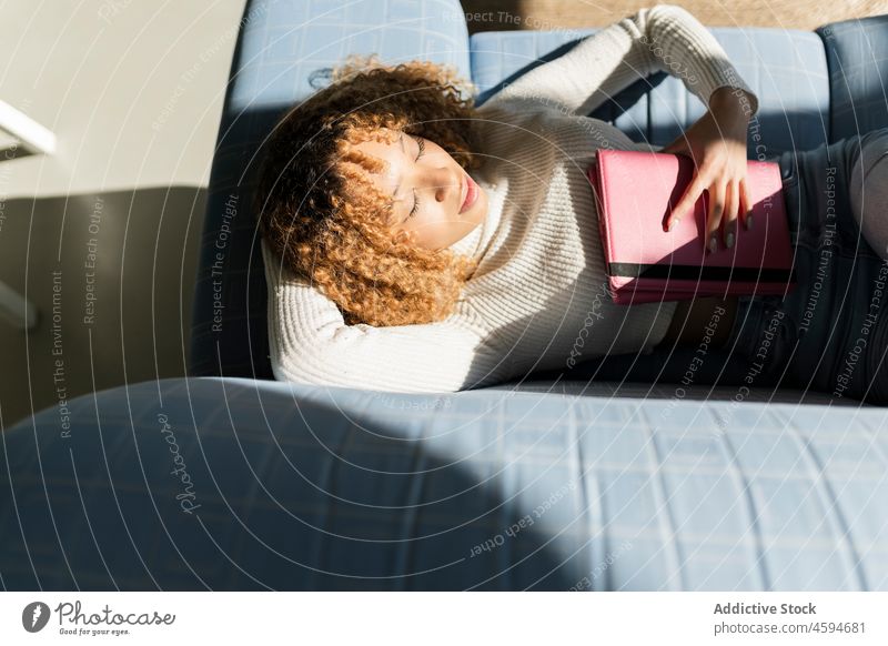 Black lady sleeping on sofa with tablet woman eyes closed couch asleep snooze comfort rest relax female nap chill ethnic gadget lounge living room exhausted