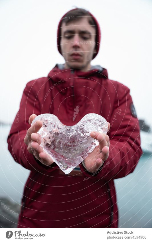 Man in outerwear showing heart shaped ice man traveler cold frozen symbol north piece male winter demonstrate frost climate tourism explore season hat