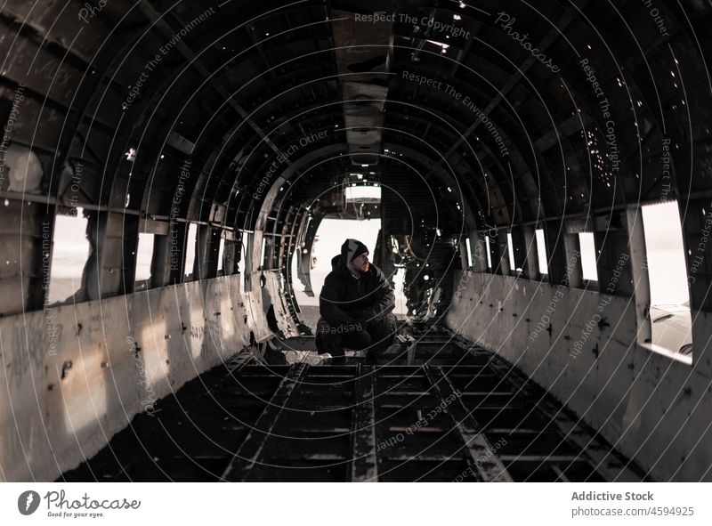 Man sitting in cabin of crashed broken aircraft man traveler accident damage plane wreckage derelict abandoned male destroy airplane adventure weathered