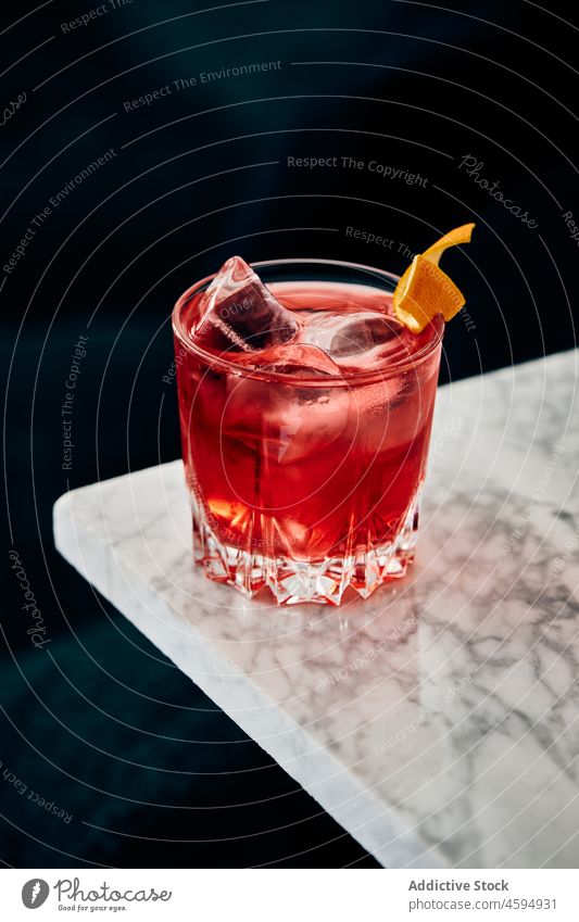 Glass of classic Negroni cocktail on marble table negroni alcohol refreshment drink beverage sofa bitter blend gin vermouth ice mix orange peel garnish citrus