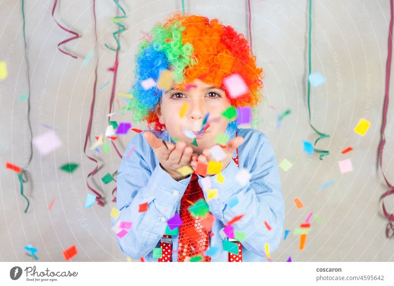 Funny boy blowing confetti at carnival birthday blast celebration child christmas clown colorful costume cute decoration entertainment expression face fun