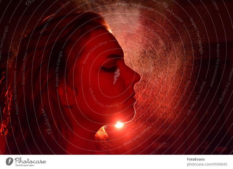 Profile of a young woman with eyes closed, using light and water spray mist Portrait photograph portrait Water Spray Woman Girl girls red Face Face of a woman