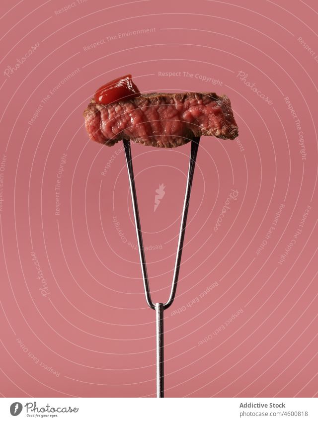 Delicious roasted meat on fork against pink background steak ketchup appetizing beef delicious tasty meal food nutrition stainless steel grill dinner gastronomy
