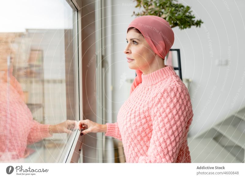 Woman in headscarf looking out window woman cancer fashion chemotherapy oncology observe thoughtful sick illness dreamy fight faith hope disease survive room