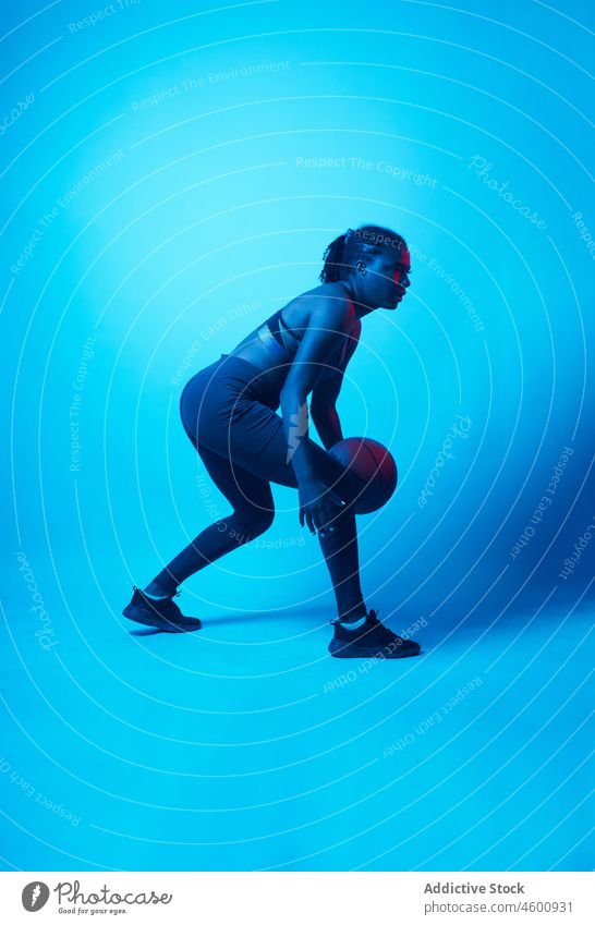 Active ethnic lady dribbling ball in studio woman dribble model play basketball game sporty fit dynamic athlete workout training female active practice physical