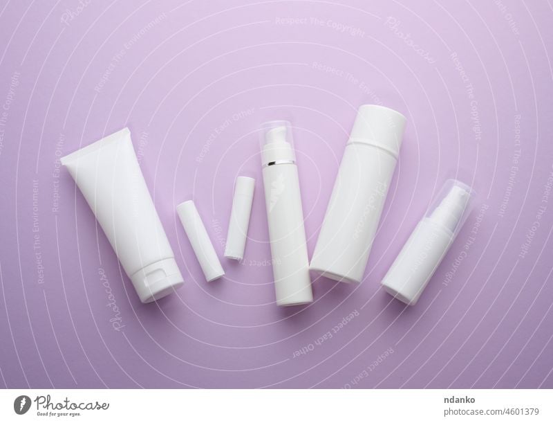 bottle and empty white plastic tubes for cosmetics on a purple background. Packaging for cream, gel, serum, advertising and product promotion beauty blank body