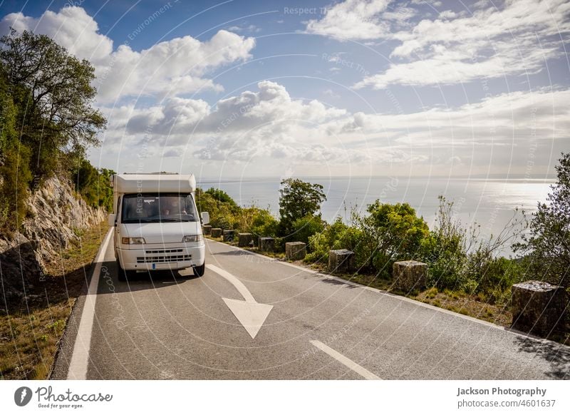 Small camper van driving on scenic road with sea views in Arrabida Natural Park, Portugal rv trip rural portugal lifestyle seafront park arrabida sesimbra day
