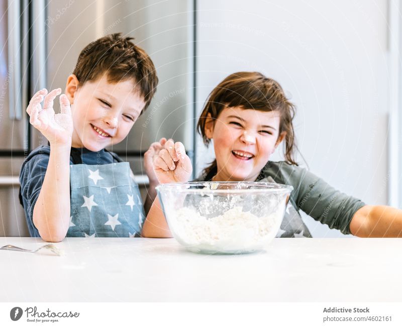 Cheerful little siblings cooking together kitchen mix culinary flour dough children kitchenware brother sister knead hand homemade bowl pastry make apron bakery