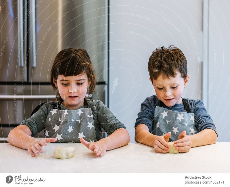 Siblings kneading dough in kitchen sibling cook boy girl culinary children together kitchenware brother sister bakery smear homemade pastry apron messy flour